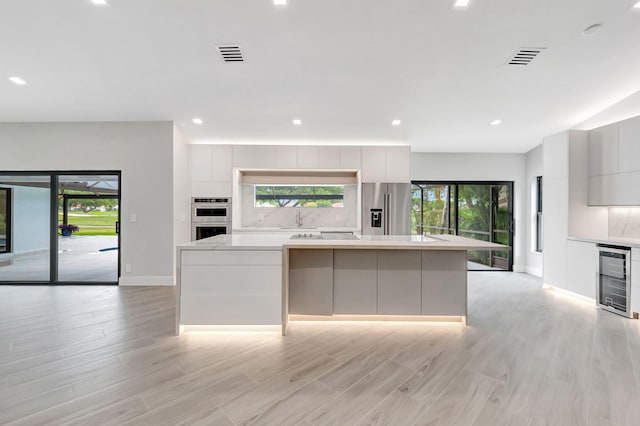 kitchen featuring a spacious island, appliances with stainless steel finishes, plenty of natural light, and wine cooler