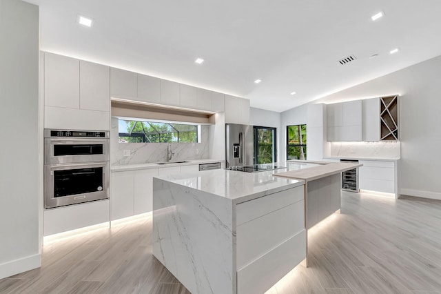 kitchen featuring sink, white cabinets, a large island, and stainless steel appliances