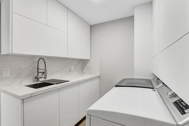 kitchen featuring sink, white cabinets, and washing machine and clothes dryer