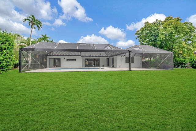 back of property with glass enclosure, a yard, and a patio