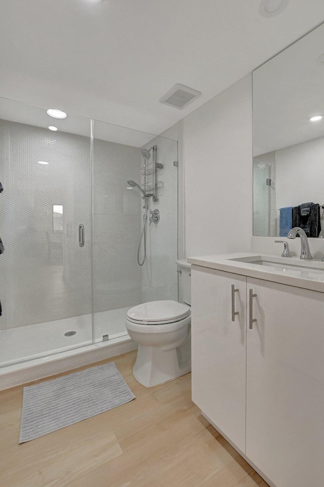 bathroom with vanity, hardwood / wood-style flooring, toilet, and walk in shower