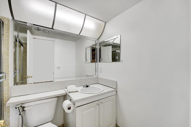 bathroom featuring toilet, vanity, and an enclosed shower