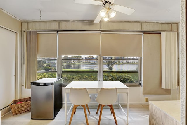 dining room with ceiling fan and a water view