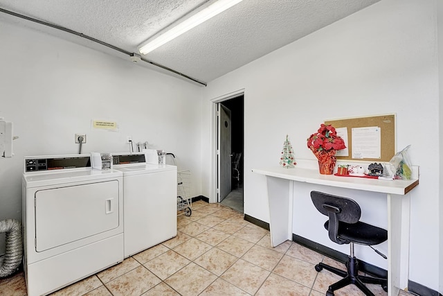 laundry room featuring washer and dryer, a textured ceiling, and light tile patterned floors