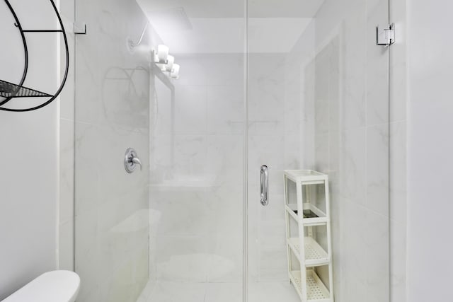 bathroom featuring a shower with door and toilet