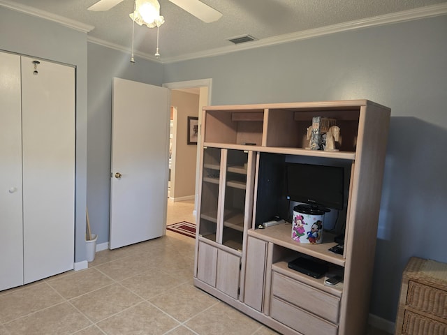 tiled bedroom with ceiling fan, a textured ceiling, a closet, and ornamental molding