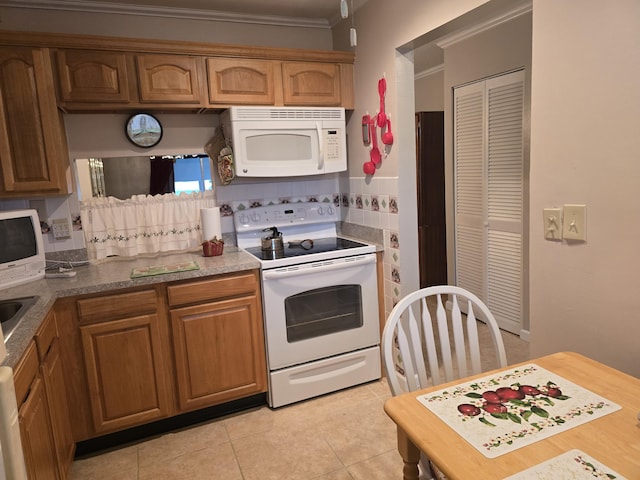 kitchen with white appliances, light tile patterned floors, and crown molding