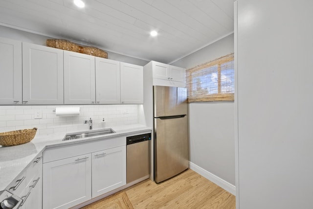 kitchen with light hardwood / wood-style floors, white cabinetry, decorative backsplash, sink, and stainless steel appliances