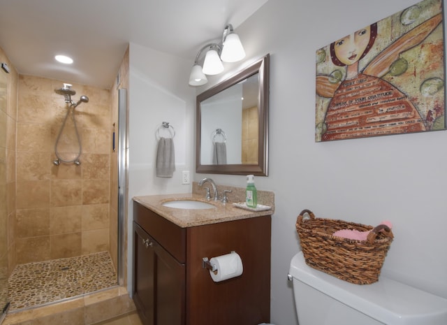 bathroom featuring vanity, tiled shower, and toilet