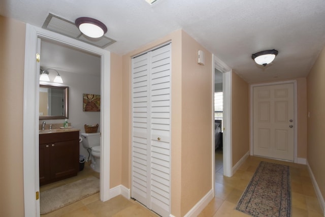 corridor with sink and light tile patterned floors