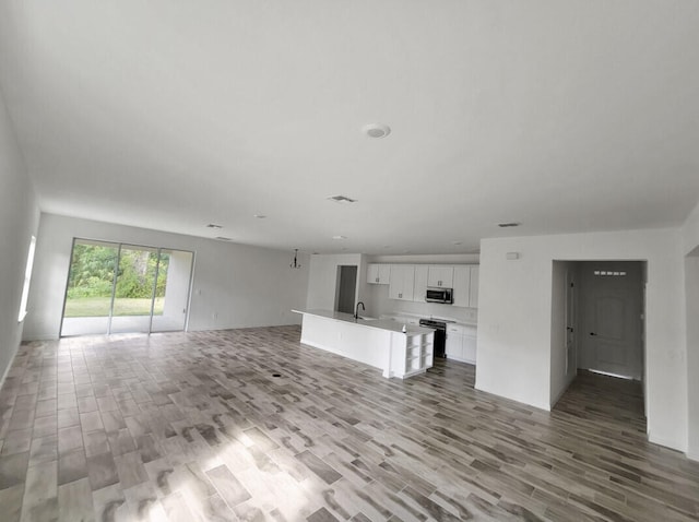 unfurnished living room featuring light wood-type flooring and sink