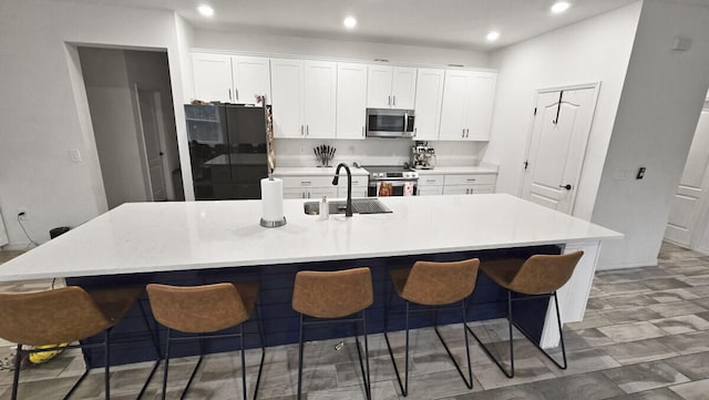 kitchen featuring a breakfast bar area, appliances with stainless steel finishes, white cabinets, and a large island