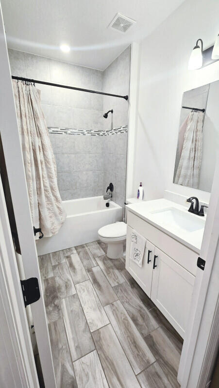 full bathroom featuring toilet, shower / bath combination with curtain, and vanity