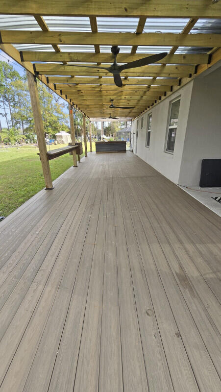 wooden deck featuring ceiling fan and a lawn