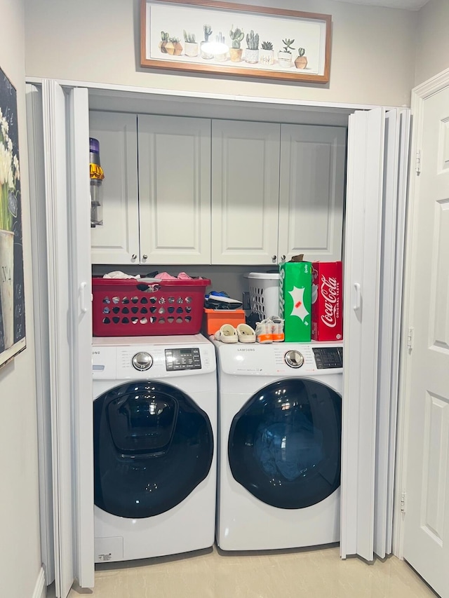 laundry area with washing machine and clothes dryer and cabinets