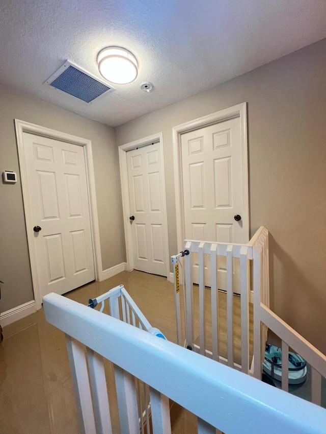 bedroom featuring a nursery area and a textured ceiling