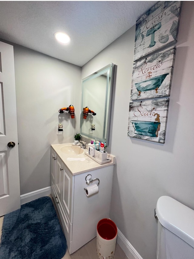 bathroom with a textured ceiling, toilet, and vanity