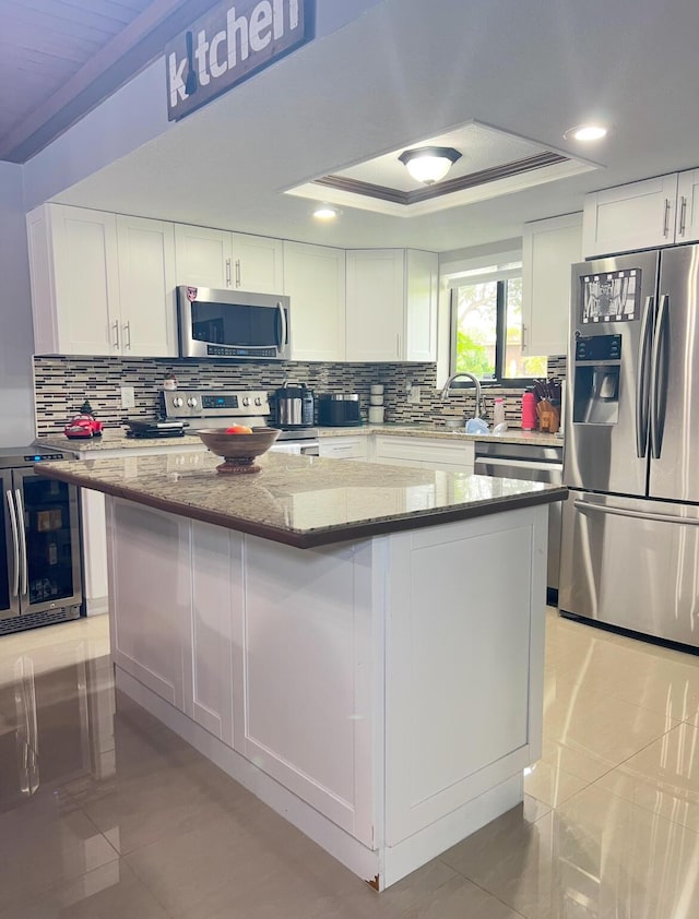 kitchen featuring light stone counters, white cabinets, a center island, and stainless steel appliances