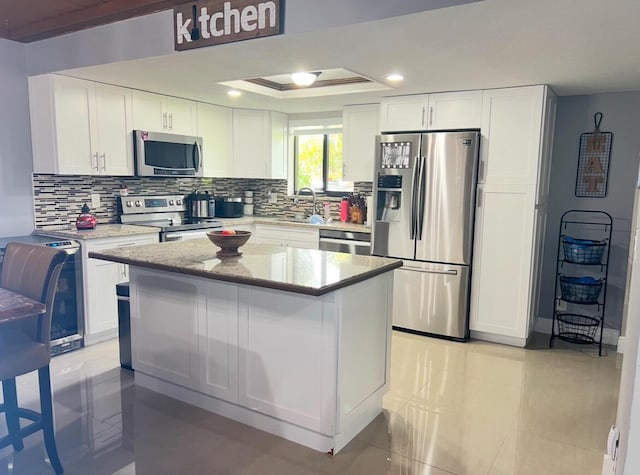 kitchen with white cabinetry, light tile patterned flooring, stainless steel appliances, and a kitchen island