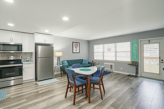 dining area featuring heating unit and light wood-type flooring