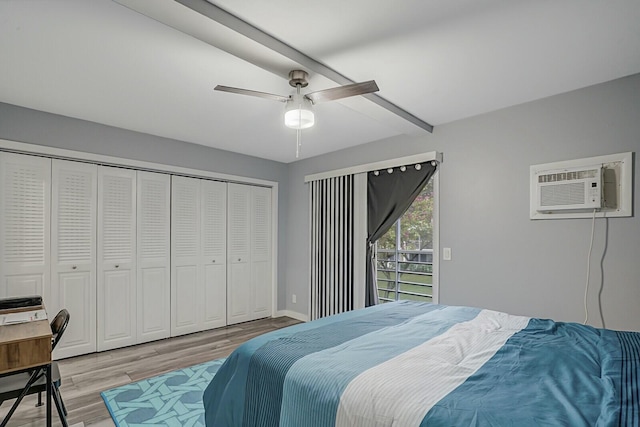 bedroom with an AC wall unit, light hardwood / wood-style flooring, ceiling fan, beam ceiling, and a closet