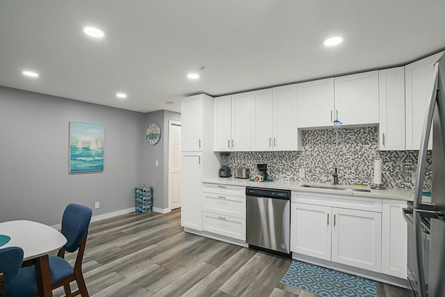 kitchen with sink, hardwood / wood-style floors, white cabinets, decorative backsplash, and stainless steel dishwasher