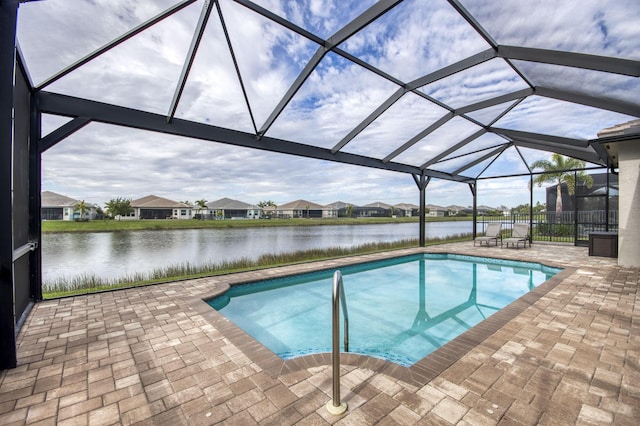 pool with glass enclosure, a patio area, and a water view