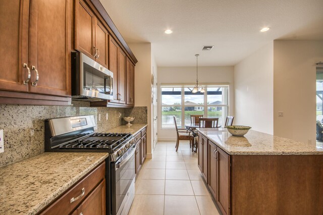 kitchen featuring light stone counters, kitchen peninsula, stainless steel appliances, and a kitchen island