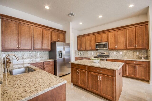 kitchen with stainless steel fridge, decorative backsplash, a tray ceiling, light tile patterned flooring, and light stone counters