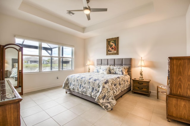 bedroom featuring ceiling fan, light tile patterned floors, and a tray ceiling