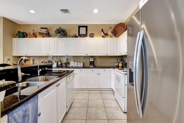 kitchen with sink, dark stone countertops, white cabinets, and white appliances