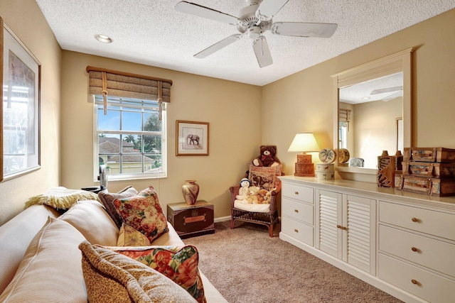 sitting room with ceiling fan, light colored carpet, and a textured ceiling