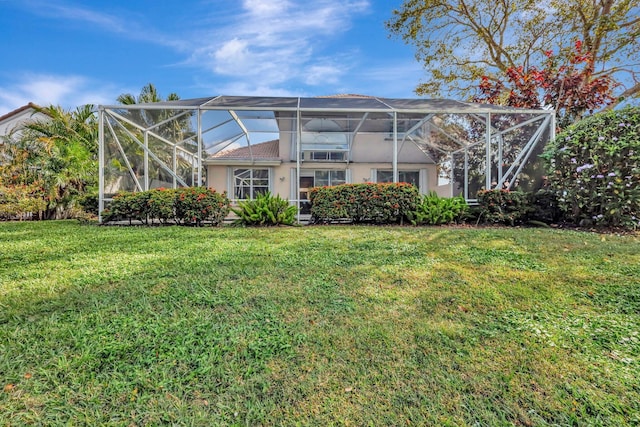 rear view of property featuring a yard and glass enclosure