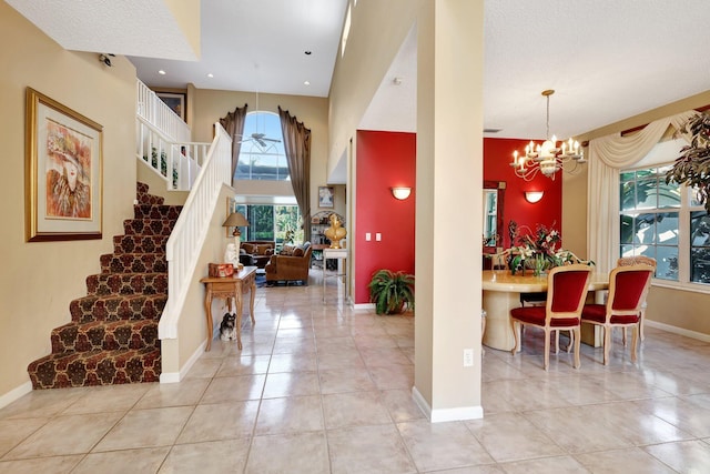 tiled entryway with a chandelier, a textured ceiling, and a high ceiling