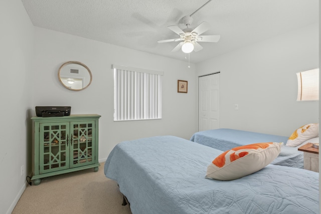 bedroom with ceiling fan, a closet, light carpet, and a textured ceiling