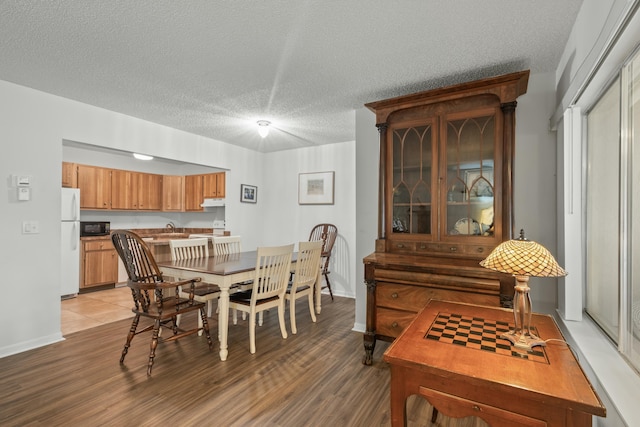 dining space featuring wood-type flooring and a textured ceiling