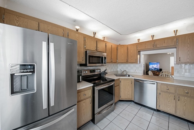 kitchen with appliances with stainless steel finishes, a textured ceiling, tasteful backsplash, light tile patterned floors, and sink