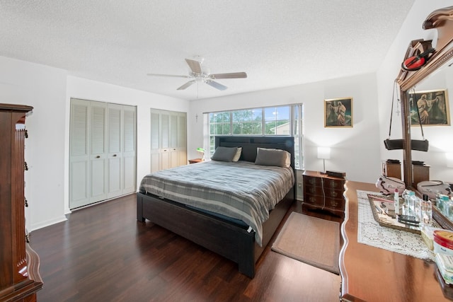 bedroom with multiple closets, ceiling fan, dark hardwood / wood-style flooring, and a textured ceiling