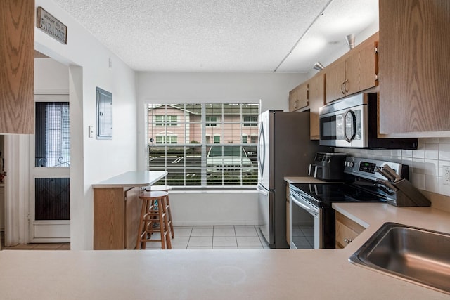 kitchen featuring appliances with stainless steel finishes, sink, electric panel, tasteful backsplash, and light tile patterned floors