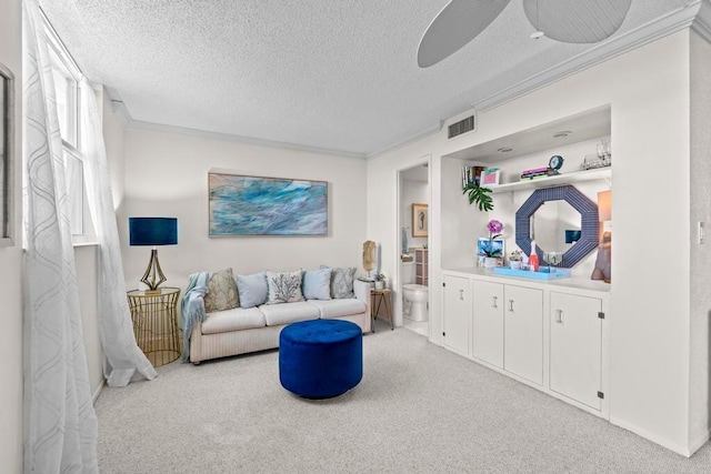 carpeted living room featuring ceiling fan, a textured ceiling, and ornamental molding