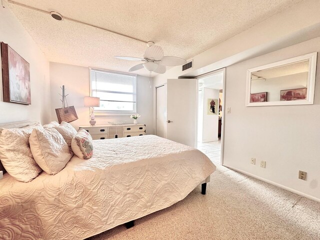 carpeted bedroom with ceiling fan and a textured ceiling