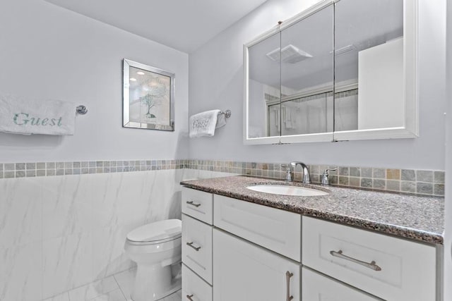 bathroom with tile walls, toilet, and vanity