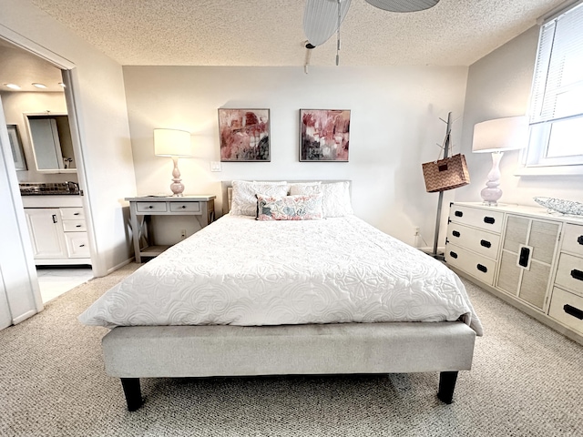 carpeted bedroom featuring ceiling fan, connected bathroom, and a textured ceiling