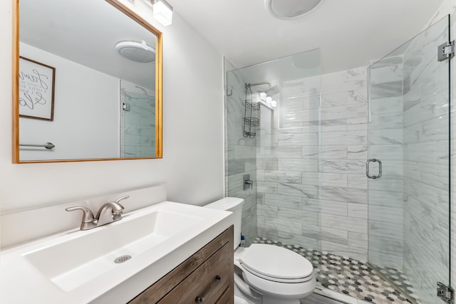 bathroom with toilet, vanity, and a shower with shower door