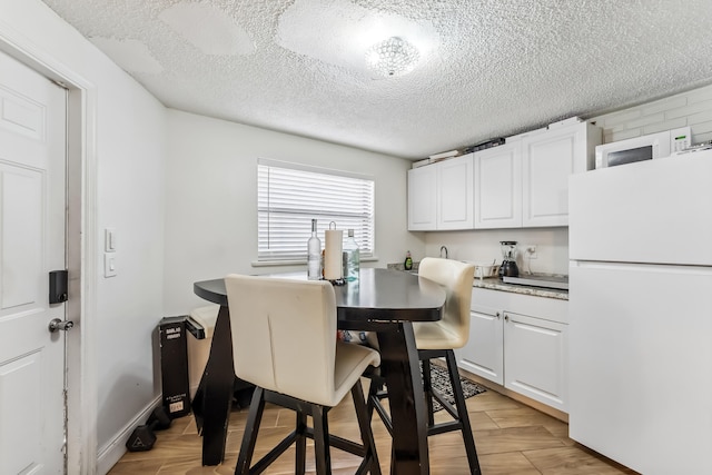 dining space featuring light wood-type flooring and a textured ceiling