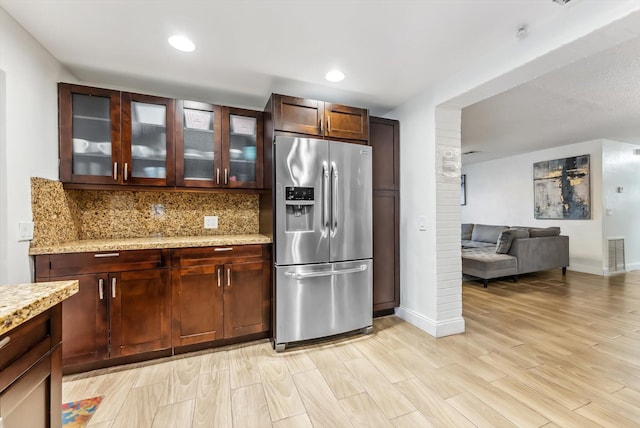 kitchen featuring light wood-type flooring, stainless steel refrigerator with ice dispenser, light stone countertops, and tasteful backsplash