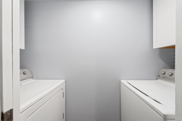 clothes washing area featuring cabinets and separate washer and dryer