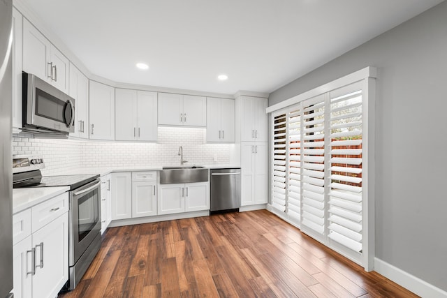 kitchen featuring sink, white cabinetry, stainless steel appliances, dark hardwood / wood-style floors, and decorative backsplash