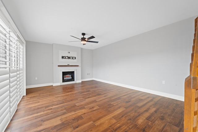 unfurnished living room featuring dark wood-type flooring and ceiling fan