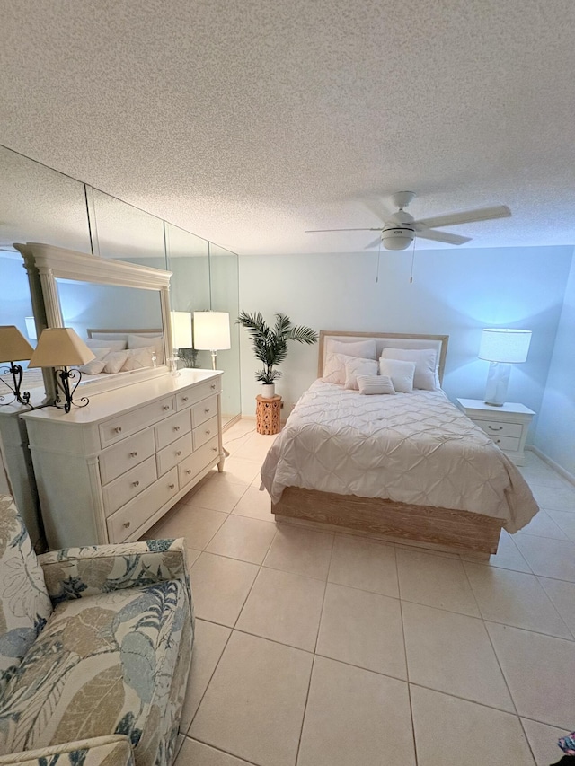 bedroom with ceiling fan, light tile patterned floors, and a textured ceiling